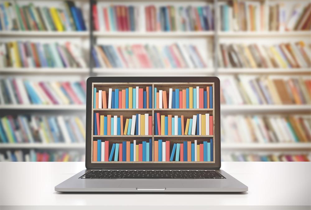 A laptop on a library with an image of nicely organized books on the laptop screen