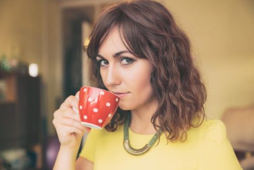 Close Up of Woman Drinking from Red Polka Dot Tea Mug and Looking at Camera